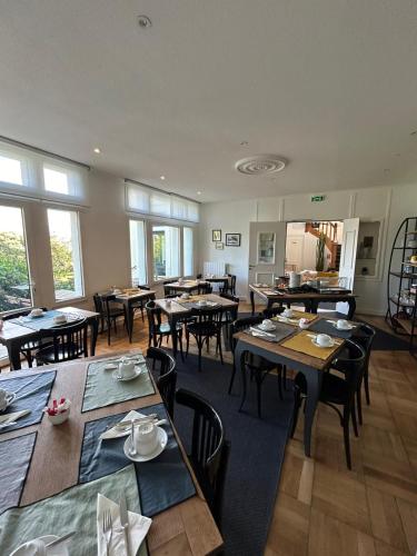 une salle à manger avec tables, chaises et fenêtres dans l'établissement Hotel de France, à Saint-Pol-de-Léon