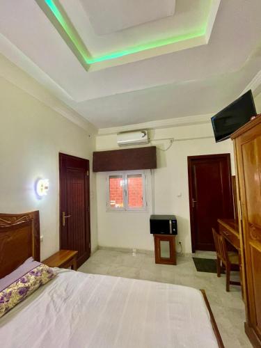 a bedroom with a bed and a desk and a tv at House of Flora in Saint-Louis