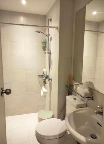 a white bathroom with a toilet and a sink at Budget Suite Paranaque in Manila