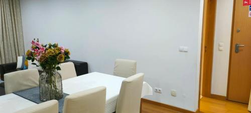 a vase of flowers on a table with white chairs at ADALBERTO NASCIMENTO LUXURY APARTA-HOSTEL At COLINAS DO CRUZEIRO in Odivelas