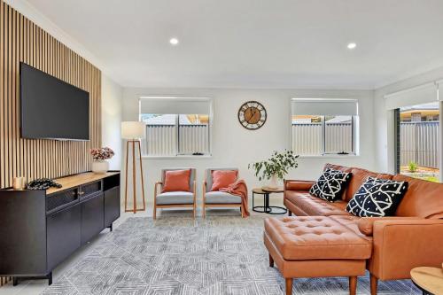 a living room with a couch and a flat screen tv at Cessnock Haven Contemporary Country Retreat in Cessnock