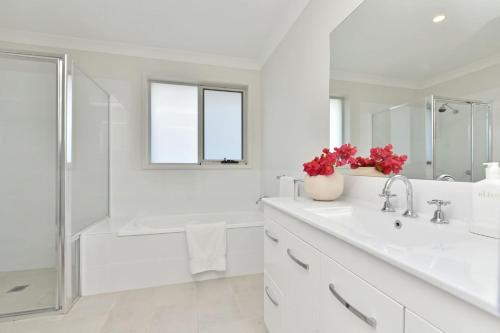 a white bathroom with a tub and a sink at Cessnock Haven Contemporary Country Retreat in Cessnock