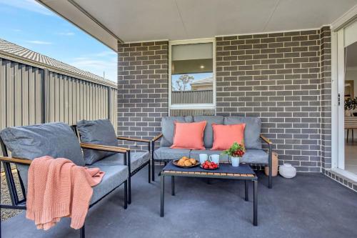 a patio with two chairs and a table with fruit on it at Cessnock Haven Contemporary Country Retreat in Cessnock
