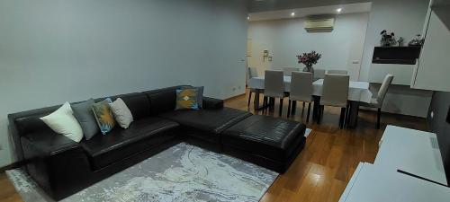 a living room with a black leather couch and a table at ADALBERTO NASCIMENTO LUXURY APARTA-HOSTEL At COLINAS DO CRUZEIRO in Odivelas
