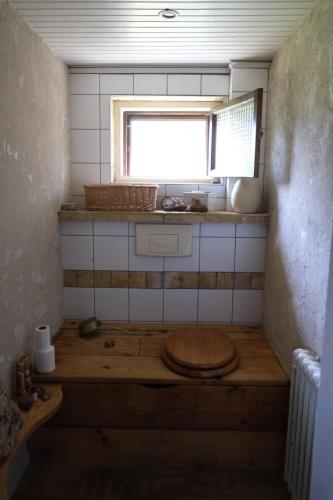 a small bathroom with a toilet with a window at L’hors-du temps in Le Tartre