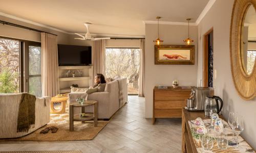a woman sitting in a chair in a living room at Oase by 7 Star Lodges - Greater Kruger Private 530ha Reserve in Hoedspruit