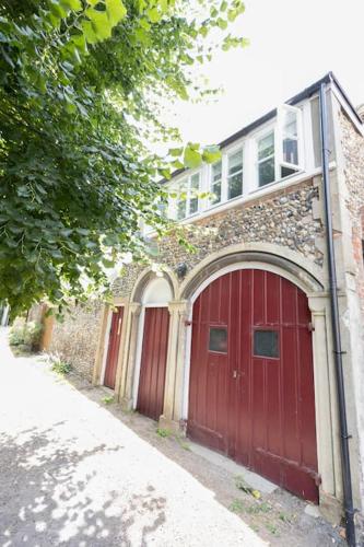 a building with a red garage door and a house at Central Medieval Grid Unique home with Gated parking in Bury Saint Edmunds