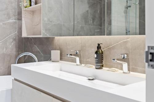 a bathroom with a white sink with a bottle of wine at Gosford Panorama Stadium & Water Views in Gosford