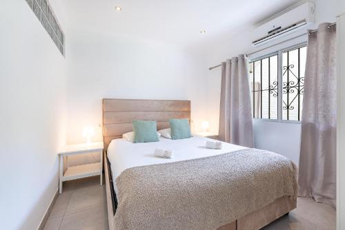 a white bedroom with a bed and a window at Benalmádena Puerto Marina Vacation Apartment 1 minute from the beach in Benalmadena Costa