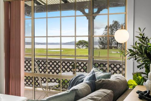 a living room with a couch in front of a large window at Driftwood Cottage Your Coastal Haven in Lemon Tree Passage