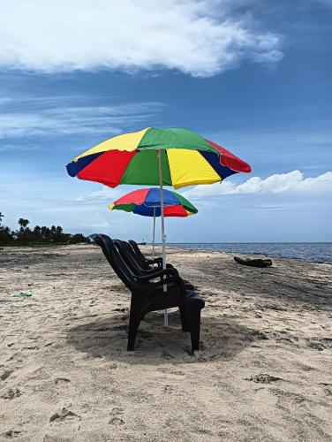 a chair sitting under an umbrella on the beach at Beach Clan Dorms in Alleppey