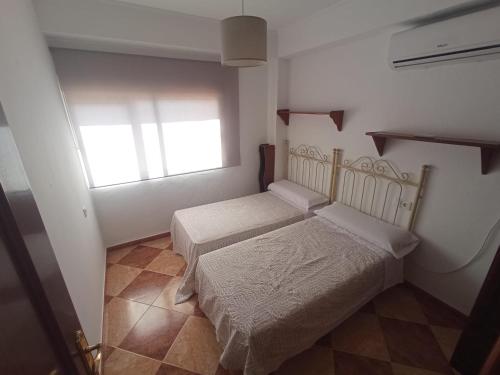 a small bedroom with two beds and a window at El Torreón 1 in Seville