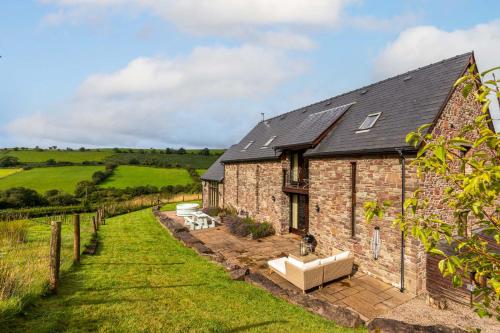 an old stone house with a garden in front of it at Hilltop View with Hot Tub in Brecon