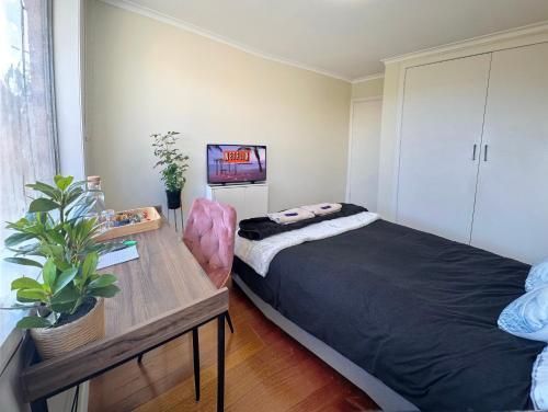 a bedroom with a bed and a table with a plant at Oakleigh Haven in Oakleigh East