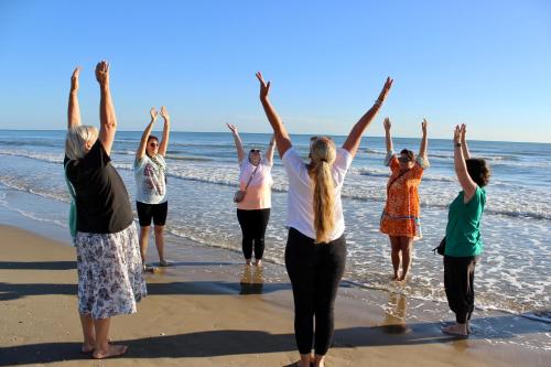 a group of people standing on the beach with their arms in the air at Aura Living Hotel in Rimini