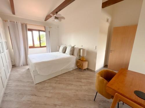 a white bedroom with a bed and a desk and a chair at Alma do Pico - Nature Residence in Madalena
