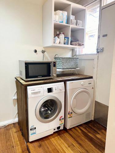 a laundry room with a microwave and a washing machine at Oakleigh Haven in Oakleigh East
