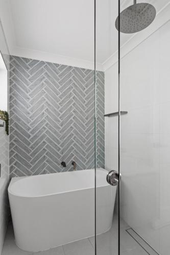 a bathroom with a tub and a glass shower at Exquisite Beachside Luxury Resort Style Pool in Wamberal North