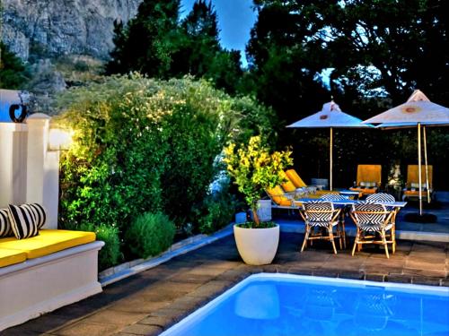 a patio with a table and chairs and a pool at Fleur du Soleil Luxury Guesthouse in Franschhoek