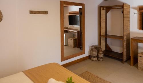 a living room with a mirror and a table at Pousada Vila do Mar in Caraíva