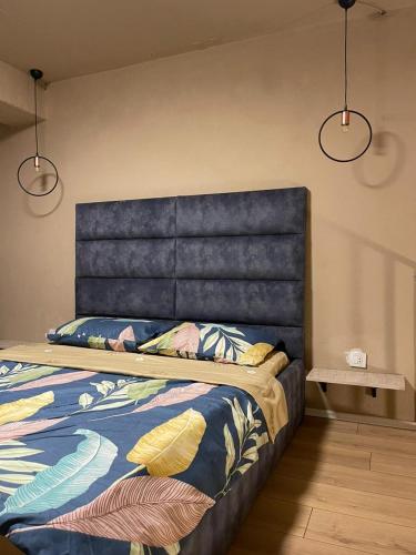 a bed with a blue headboard in a room at Zen Apartments Pejë in Peje