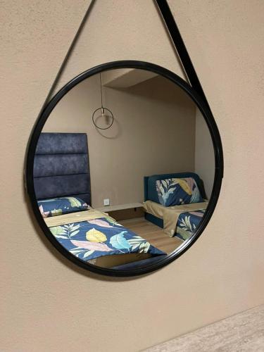 a mirror reflecting a bedroom with a bed and a chair at Zen Apartments Pejë in Peje