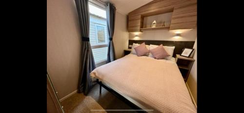 a small bedroom with a bed with a window at R&R Coastal Retreats Cedars 63 in Skegness