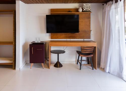 a room with a desk with a television and a stool at Pousada Vila do Mar in Caraíva