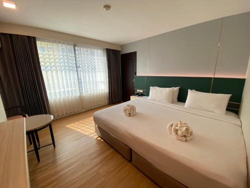 a bedroom with a large bed with two pillows on it at Mayflower Grande Hotel Phitsanulok in Phitsanulok