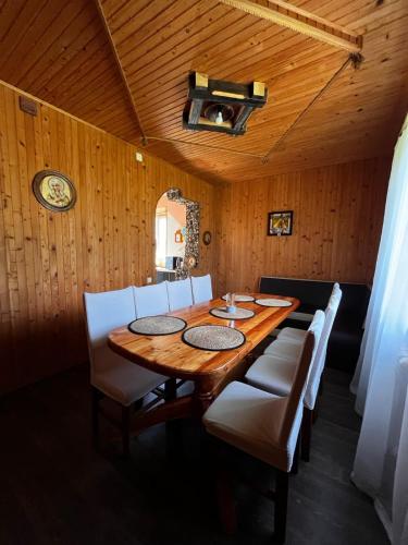 a dining room with a wooden table and white chairs at Карпатський двір in Krivorovnya