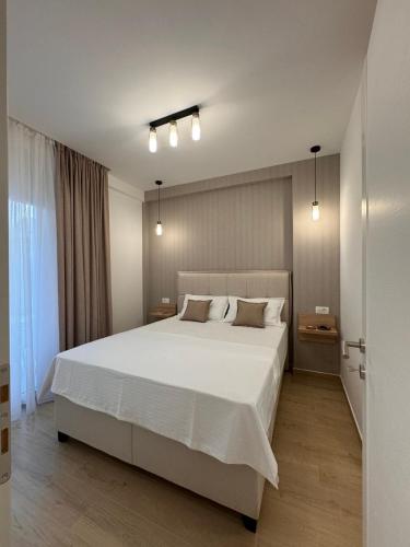 a bedroom with a large white bed and a window at DMM Apartments in Tivat