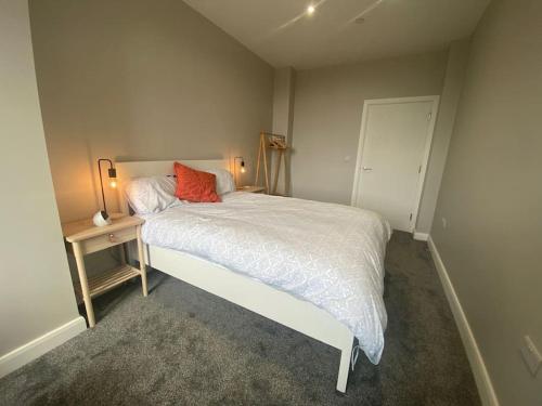a bedroom with a bed with a red pillow on it at Chic Mill conversion beside Piece Hall & Eureka! in Halifax