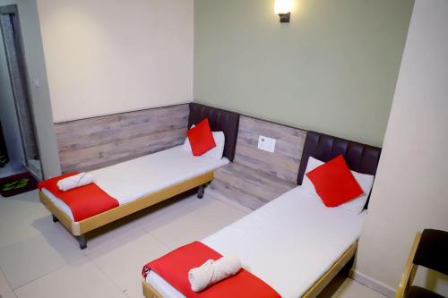two beds in a room with red pillows on them at Hotel Mansi in Vapi