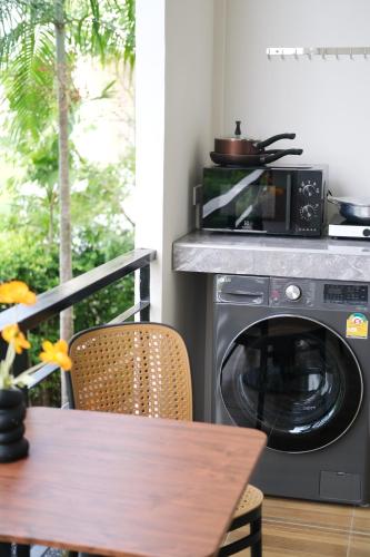 a kitchen with a washing machine and a table at Alisse Stay Phuket Layan in Phuket