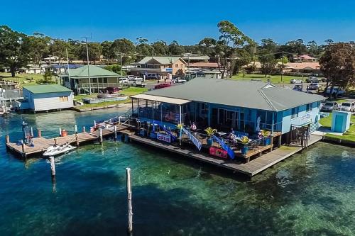 a house on a dock in the water at Meroo Meadow Magic Charming Cottage Retreat in Meroo