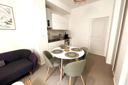 a living room with a table and chairs and a couch at Charmant appartement Près de la Gare in Saint-Quentin