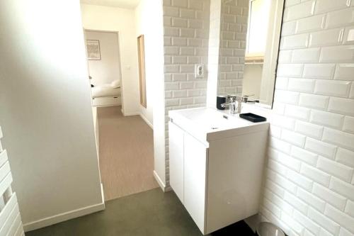 a white bathroom with a sink and a mirror at Charmant appartement Près de la Gare in Saint-Quentin