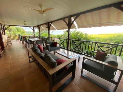 a room with couches and tables on a balcony at Colibri Villa Sainte Luce in Sainte-Luce