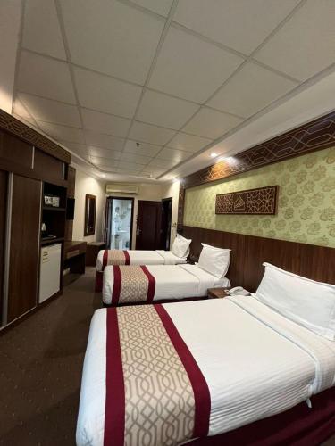 a hotel room with three beds and a kitchen at Mahd Al Resala 1 Hotel in Mecca