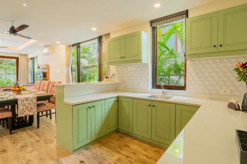 a kitchen with green cabinets and a dining room at ELIVAAS 3 BHK Pvt Pool & Bar - Villa Valerie in Oxel