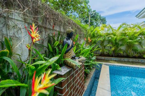 a statue sitting next to a swimming pool at ELIVAAS 3 BHK Pvt Pool & Bar - Villa Valerie in Oxel