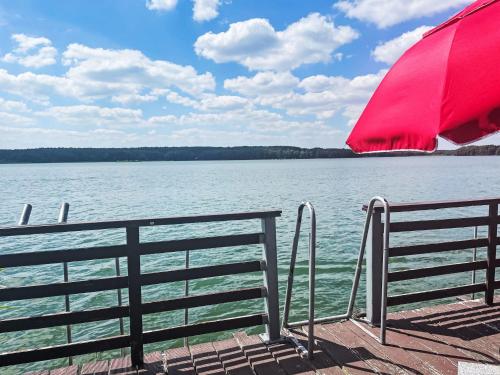 a red umbrella sitting on a dock next to the water at Chalet Bootshaus auf dem See by Interhome in Lindow