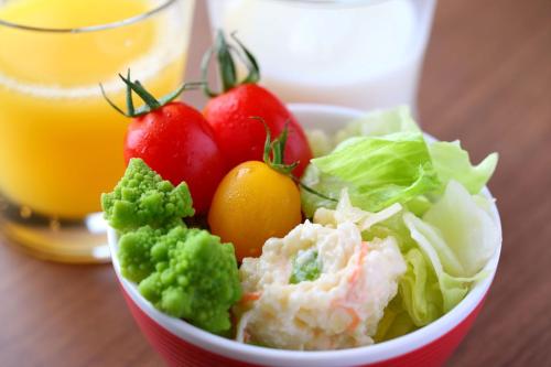 a bowl of vegetables and a glass of orange juice at Almont Inn Shonan Fujisawa in Fujisawa