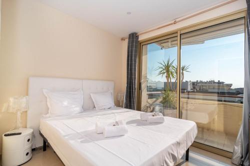 une chambre avec un lit blanc et une grande fenêtre dans l'établissement Wow Splendide 3-4 pcs Duplex Rooftop Vue mer by Olam Properties, à Cannes