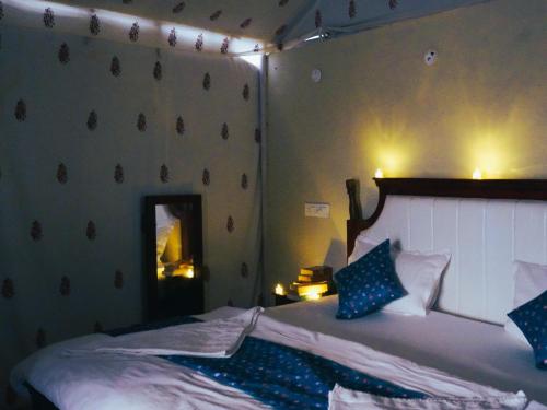 una camera da letto con un letto con cuscini blu e bianchi di Dune Delite Jaisalmer a Sām