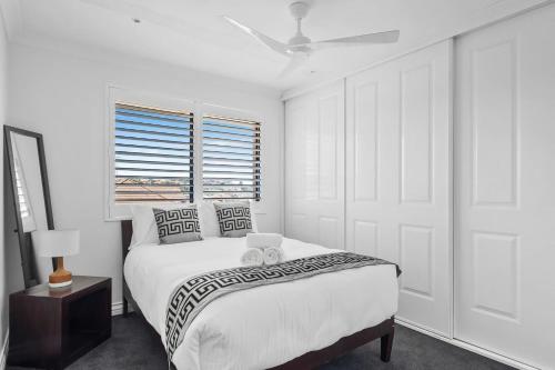 a white bedroom with a bed and a window at Dream View Steps from the Beach in Sydney
