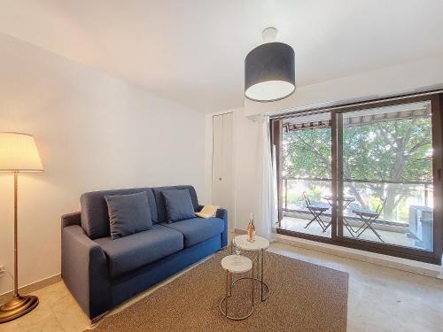 un salon avec un canapé bleu et une grande fenêtre dans l'établissement Nestor&Jeeves - KALLISTA - Central - Balcony, à Nice