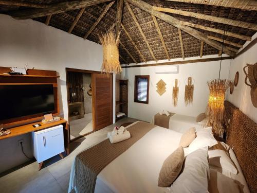 a bedroom with a large bed and a flat screen tv at Pousada Vila do Mar in Caraíva