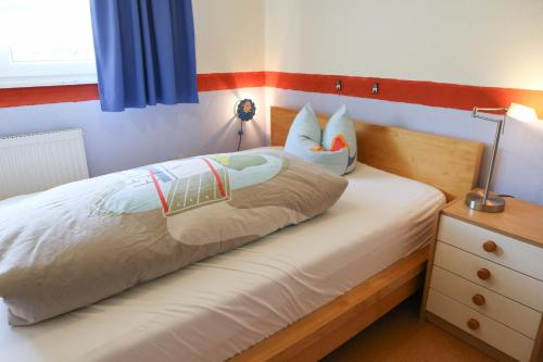 a bedroom with a bed and a nightstand with a lamp at Ferienwohnungen Porisch in Egloffstein
