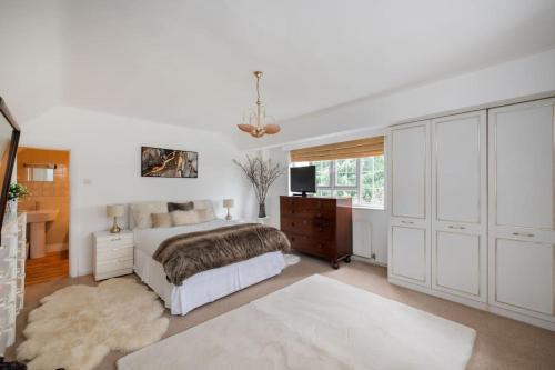 a bedroom with a bed and a desk and a television at 5 Bed Home with Private Parking - 25 Mins To Central London in Cockfosters